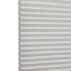 White cellular (honeycomb) blind, left-edge visible with uniform horizontal pleats; fully lowered and closed, softly filtering daylight; set against a bright, neutral interior background.