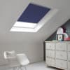Room with white eaves wall, dark blue-grey wall to right with a shabby chic white drawer unit, a contemporary white chair, white painted floorboards and a skylight blind in ink blue.