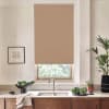 Beige roller blind covers most of a kitchen window, blocking light above a stainless sink and faucet; countertop holds bowl of leafy greens, potted plants, towel, framed sketch on wall.