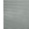Light-gray pleated cellular (honeycomb) blind, tightly closed with visible hexagonal cells at left edge; filtering/diffusing light, photographed close-up filling the frame against a white background.