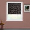 Black Roman shade with white triangular pattern and red accents, lowered, filtering daylight; mounted in a white frame on a mauve wall with framed art and a side table.