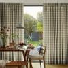 Beige plaid pleated curtains, mostly drawn with a central gap revealing the outside; filtering soft morning light over a wooden dining table set for breakfast, pendant lamp, and garden view.