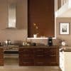 Dark brown horizontal venetian blinds covering a window, fully closed and filtering warm light; modern kitchen with dark wood cabinets, stainless-steel range and hood, countertop appliances, potted orchid on sill.