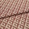 Woven upholstery fabric with repeating terracotta-and-cream triangular motif, folded once across the frame, revealing textured weave and raised pattern; close-up, evenly lit studio shot on neutral surface.