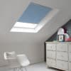 Room with white eaves wall, dark blue-grey wall to right with a shabby chic white drawer unit, a contemporary white chair, white painted floorboards and a skylight blind in mid blue.