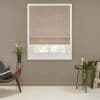 Beige fabric Roman shade, partially lowered with soft horizontal folds, filtering daylight through a lower gap; set on a taupe wall in a neutral living room with mid-century chair, plants, and side table.