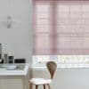 Sheer mauve Roman blind, lowered and softly filtering daylight; wooden chair and white desk beside window, pendant paper lamp overhead, minimalist home office with pale walls and bare tree view.