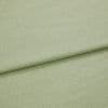 Pale green woven fabric folded once, showing a horizontal overlap and subtle textured weave; lying flat in soft, even studio lighting with a neutral background.