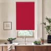 Red roller blind covers window above sink, blocking most light; stainless faucet and double basin sit on marble countertop surrounded by wooden cabinets, potted plants, and framed sketch.