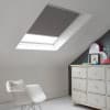 Room with white eaves wall, dark blue-grey wall to right with a shabby chic white drawer unit, a contemporary white chair, white painted floorboards and a skylight blind in mid slate grey.