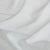 Sheer white curtain fabric, layered and draped in soft folds, gently filtering diffuse daylight; close-up interior window treatment showing subtle linen texture and delicate translucence.