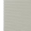 Cream cellular (honeycomb) window blind, fully lowered with visible hexagonal pleats at the left edge; closed and diffusing light; close-up against a plain white background with soft lighting.