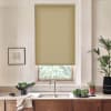 Beige roller blind is partially lowered over a window above a kitchen sink; sunlight filters through while the countertop holds a bowl of greens, potted plants, a framed sketch, and a faucet.