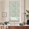 Patterned roller blind covers a window above a sink; faucet centered on a marble countertop with wooden cabinets, bowl of leafy greens, potted plants and framed sketch on wall.