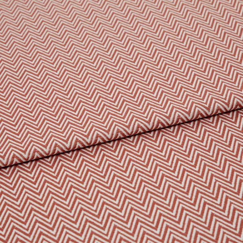 Chevron-patterned textile (red and white) folded across the frame, showing tight zigzag lines; fabric lies flat with a single fold, photographed in even studio lighting on a neutral background.