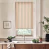 Striped roller blind covers top of a kitchen window, light visible through lower pane; stainless faucet and sink below, countertop with bowl of greens, framed sketch left, potted plants right.