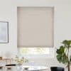 Beige pleated cellular blind lowered, with horizontal ribs and faint vertical cord lines, filtering soft daylight; over a bright minimalist dining nook with round table, vase, glassware and fiddle‑leaf fig.