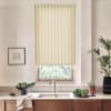 Yellow-striped roller blind lowers over a window above a stainless sink, filtering daylight into a minimalist kitchen with wooden cabinets, countertop plants, a bowl of greens, and a framed sketch.