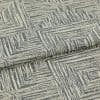 Woven upholstery fabric, cream base with gray, hand-drawn concentric-square pattern, folded over itself; photographed close-up under neutral studio lighting, showing textured weave and a layered edge.
