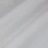 Object: white semi-sheer fabric (curtain-like) with stitched hem and faint grid texture. Action: layered into broad diagonal folds. Context: close-up view, soft diffuse lighting, neutral background.
