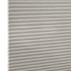 Light-gray pleated cellular window shade, closed with visible honeycomb cells and fabric texture; blocking light and insulating; shown close-up against a neutral, evenly lit backdrop.