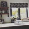 Patterned fabric Roman blind, partially lowered across a black-framed double window, filtering bright daylight; stainless spring-tap over kitchen sink, potted plants, soap bottles and wooden mug shelves nearby.
2019
NOV
2
SAT
PM
DISH SOAP
HAND SOAP
