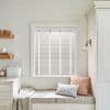 White horizontal Venetian blinds inside the window frame with narrow vertical tapes — closed, filtering soft daylight — above a cozy kitchen window seat with cushions, pale cabinetry, and a wall sconce.
BREAD
