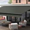 Dark green retractable awning with metal front bar and straight valance, fully extended over glass patio doors, shading a modern outdoor seating area with sofa, chairs, and coffee table, daytime.