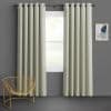 Grommet-top pale sage curtains, floor-length with deep pleats, hung on a metal rod and parted slightly, filtering soft daylight over a gray-walled room with gold wire chair and abstract art.