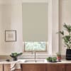 Beige roller blind covers a kitchen window above a stainless sink, blocking light; wooden countertop with dish towel, bowl of greens, potted plants and framed sketch on pale wall.