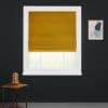Mustard-yellow Roman shade, folded and lowered to mid-window, partially blocking and filtering daylight; set in a white frame on a dark wall, with a small wooden side table, abstract art.