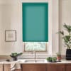 Teal roller blind covers most of a kitchen window above a faucet and sink, countertop holding a bowl of leafy greens, potted plants, and a framed sketch on the wall.