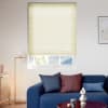 Cellular blind, pale yellow, lowered across a recessed window, filtering light and leaving the lower pane exposed; living room with blue sofa, cushions, floor lamp, wooden sideboard, coffee table.