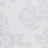 White lace-like fabric with rose and honeycomb motifs, showing an embossed floral pattern, presented in a tight close-up under soft, even diffuse lighting on a neutral background.