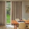 Floor-to-ceiling checkered brown-and-cream pleated curtains, drawn aside to reveal a narrow four-pane window, filtering daylight; a sunlit dining room with wooden table, beige chairs, lawn and tree outside.