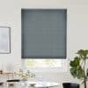 Gray cellular blind lowered over window, horizontal folds with vertical stitch lines, mostly closed with a narrow band of daylight; minimalist dining area with table, vase, and fiddle‑leaf fig.