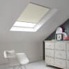 Room with white eaves wall, dark blue-grey wall to right with a shabby chic white drawer unit, a contemporary white chair, white painted floorboards and a skylight blind in linen-cream.