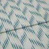 Folded woven fabric with teal ikat-like diagonal stripes and subtle vertical ribbing — folded once, lying flat on a neutral surface, close-up, soft even lighting.