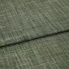 Green crosshatched woven fabric, folded in overlapping layers, displaying textured beige and olive threads; tightly lit close-up emphasizing the weave and subtle sheen on a neutral surface.