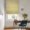 Yellow patterned Roman blind lowered over the window, softly filtering daylight; a desk with mirror, vase of flowers and teal chair fills a bright, minimalist home office overlooking a garden.