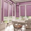 Purple horizontal venetian blinds covering tall bay windows and French doors, partially lowered and filtering soft daylight, in a bright white dining nook with table, chairs, cushions and garden view.