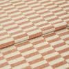 Folded woven fabric with peach‑terracotta and cream rectangular stripe pattern, textured surface; layered folds overlapping; close-up studio-lit view showing a textile sample and detailed weave.