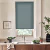 Teal cellular window shade is lowered over a kitchen window, revealing greenery through the lower pane; stainless faucet and sink rest on a stone countertop with bowl and potted plants.