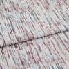 Light-colored textured woven fabric with vertical, streaky maroon and teal lines, folded across itself, lying flat in a close-up studio shot with soft, even lighting.