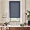 Navy roller blind lowered over a window framing leafy trees. Below, stainless faucet over double sink on stone counter, with bowls of greens and potted plants.