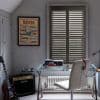 Wooden interior plantation shutters cover a double window, closed with slats angled to filter daylight; set above a glass desk in a grey home office with a chair, guitar and amplifier.
ROVER
Marshall
