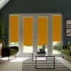 Four orange roller blinds cover tall patio doors, partially lowered to reveal a green garden outside; modern living room with green armchairs, glass coffee table and chevron rug.