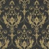 Ornate gold damask motifs—stylized leaves and scrolling flourishes—repeat symmetrically, adorning a flat, distressed charcoal wall surface, suggesting vintage, formal wallpaper in a dimly lit interior.