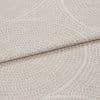 Beige textured fabric with pebble‑like raised dots and subtle curved lines; folded horizontally across the frame; close-up studio shot showing layered upholstery material in even, soft lighting.