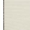 Cream cellular (honeycomb) blind with dark-lined cells visible on the left; closed into uniform horizontal pleats, filtering soft diffuse indoor light against a neutral background.